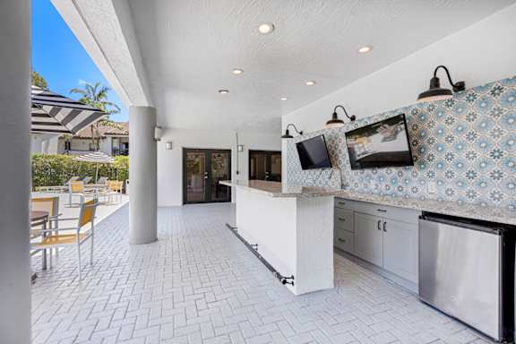 covered outdoor kitchen with TVs