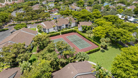 A tennis court is surrounded by apartments and trees.