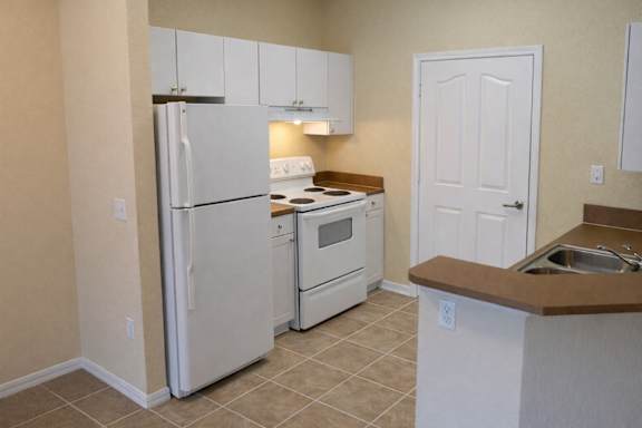 A kitchen with a white refrigerator, oven, and sink.