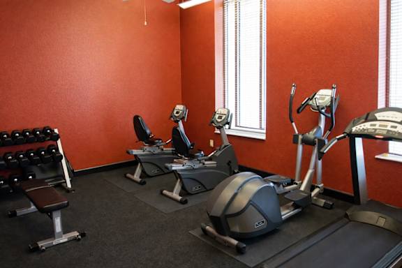 A gym with orange walls and a variety of exercise equipment.
