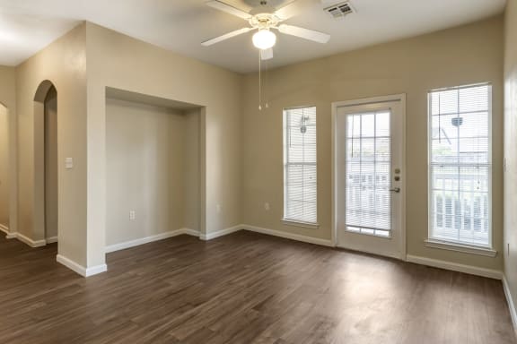 an empty living room with a ceiling fan