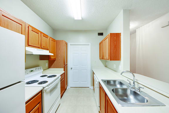 A kitchen with white appliances and wooden cabinets.