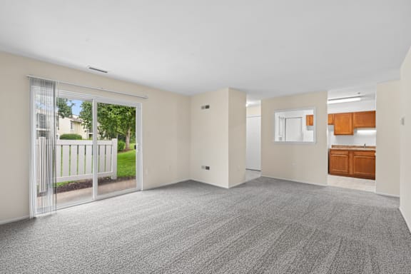 A spacious room with grey carpeting and white walls.