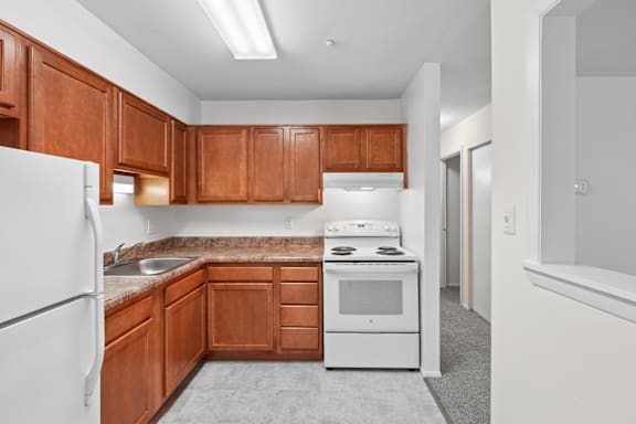 A kitchen with brown cabinets and white appliances.