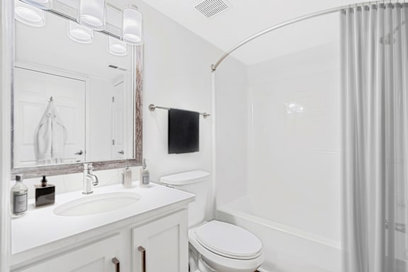 a bathroom with a white sink and toilet and a white bathtub with a shower curtain at Caveness Farms Apartments, North Carolina, 27587