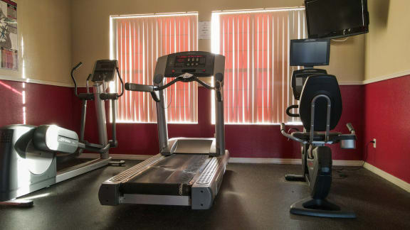 Fitness center with treadmill, exercise bike, elliptical, and tv mounted on wall
