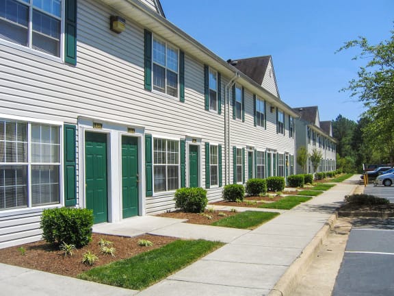 a long white building with green doors and shutters