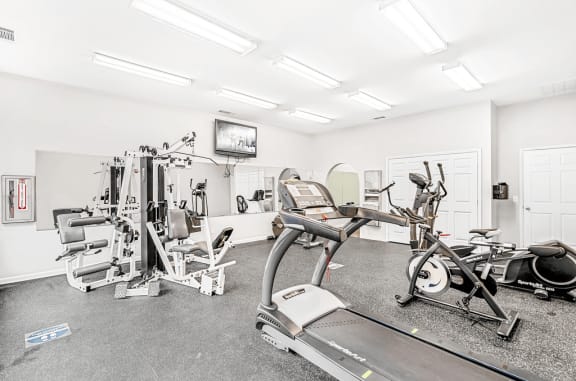 Bright Fitness Center with Exercise Equipment and Mirrored Wall and Mounted TV