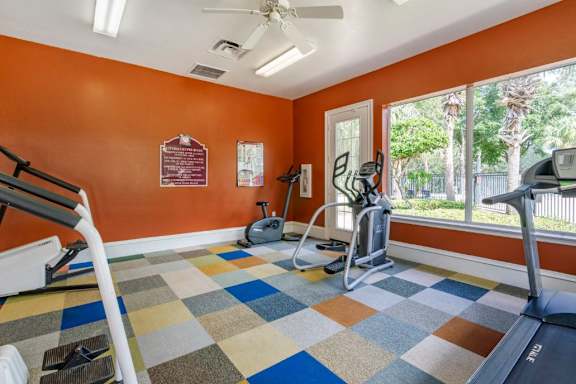 Fitness center with cardio equipment and large windows for natural lighting