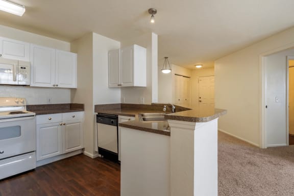 Kitchen with white appliances, hardwood style flooring, and white cabinets