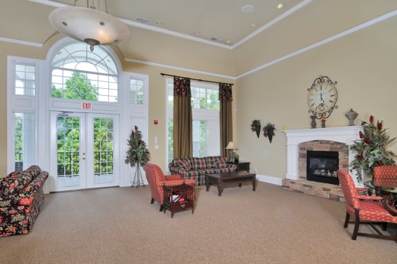 Resident clubhouse with seating throughout including multiple couches and chairs. A fireplace rests to the right of the room