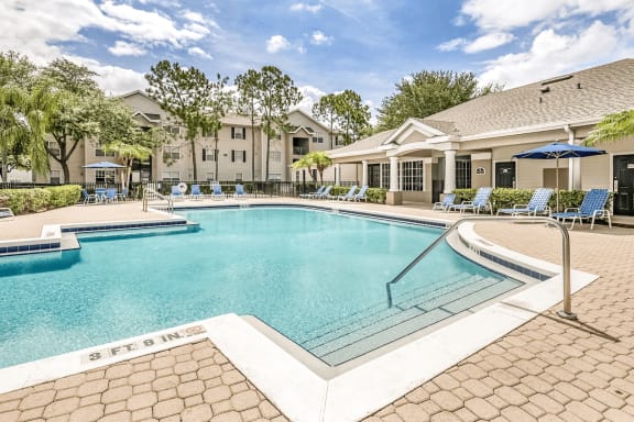 Swimming pool with lounge seating and clubhouse in the background