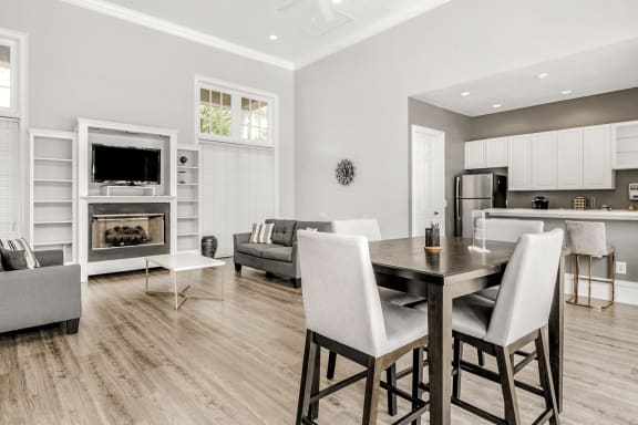 Clubhouse lounge with cafe style seating, hardwood style flooring, couches, chairs, fire place and wall mounted television