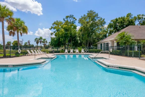 Swimming Pool and Sun Deck with Lounge Chairs with Trees and Building Exteriors in the Background