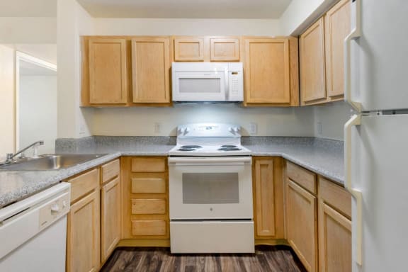 Kitchen with Blonde Cabinets Grey Counters and White Appliances