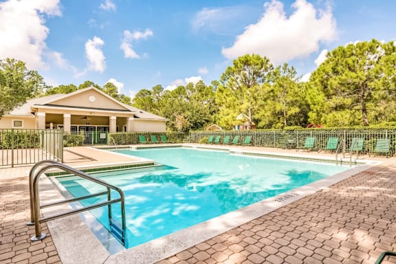 Swimming pool with a brick paver sundeck and lounge chairs outside the clubhouse.
