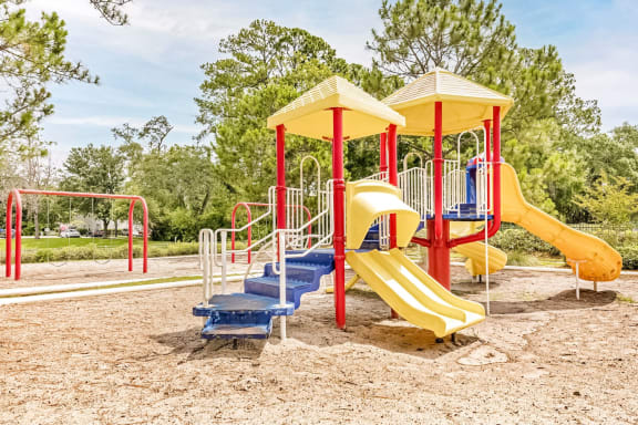 Large playground structure with several yellow slides and a red swing set.
