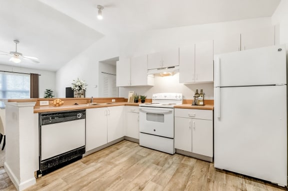 Staged  kitchen with white appliances, white cabinets, and hardwood-style flooring.