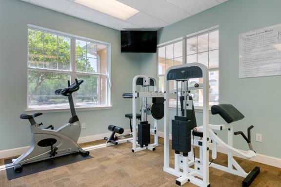 Fitness center equipped with strength training equipment, cardio equipment, and mounted tv