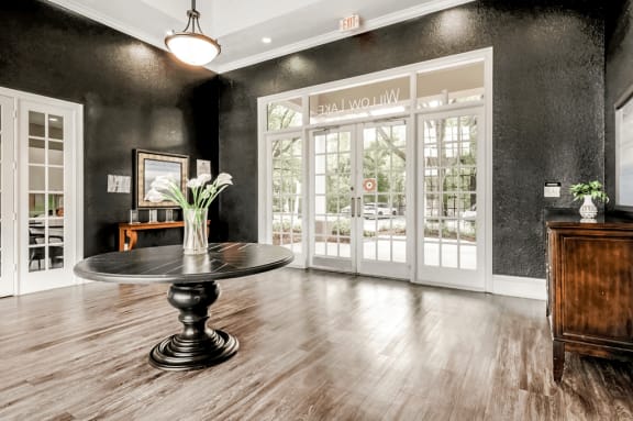 Clubhouse interior entryway with dark colored walls, brown dresser, black table with floral decor