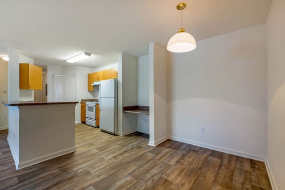 Dining Room with wood floors, white walls, and built in desk with view of the kitchen in the back