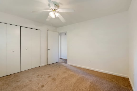 Carpeted Bedroom with white walls and one widow, double door closet, and ceiling fan