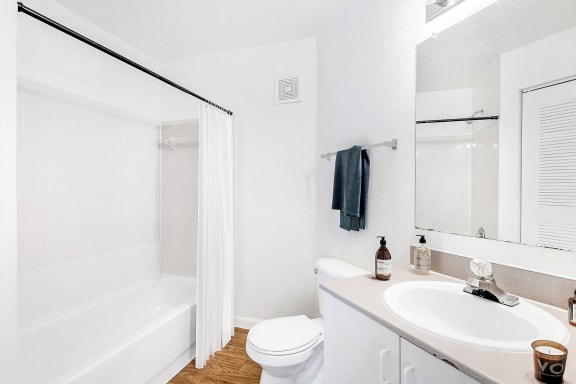 Staged Bathroom with vanity, mirror, and a tub/shower combo. Rolled towels and décor above vanity with art on the wall.