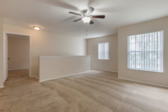 Living room with carpet flooring, multi speed ceiling fan, and large windows for natural lighting
