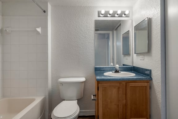 Bathroom with large mirror, vanity lighting, and tiled shower