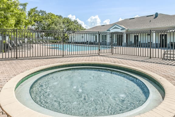 Gated wading pool with swimming pool and deck in background and surrounding native landscape