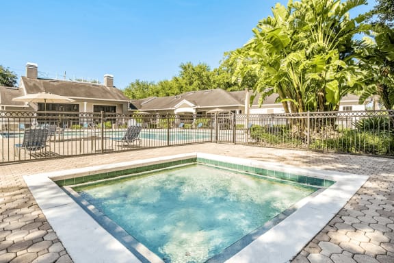Gated wading pool with swimming pool and deck in background and surrounding native landscape