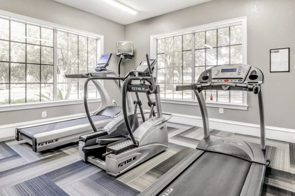 Fitness center with cardio machines, large windows and television