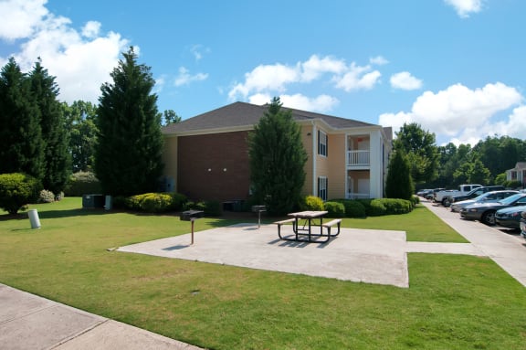 Picnic area by a community grill next to apartment building