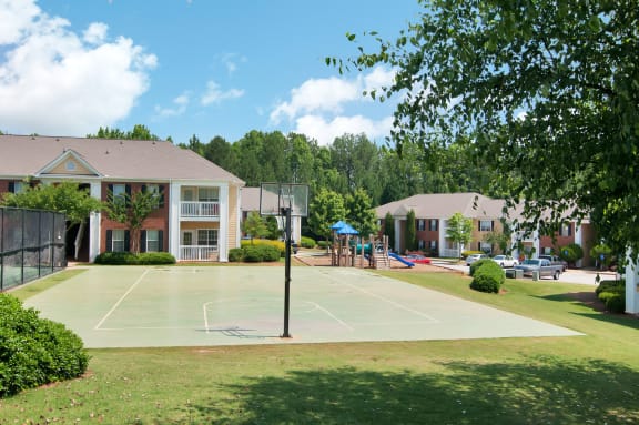 tennis court with apartment buildings in the background with trees