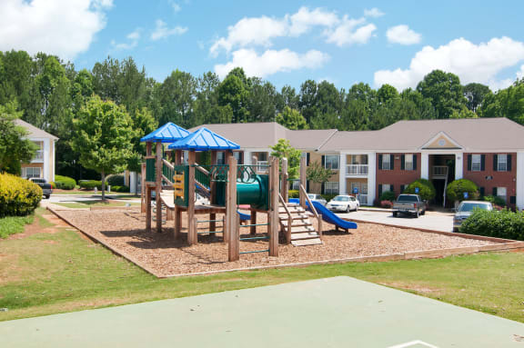 Playground with wood chips in court yard between buildings.