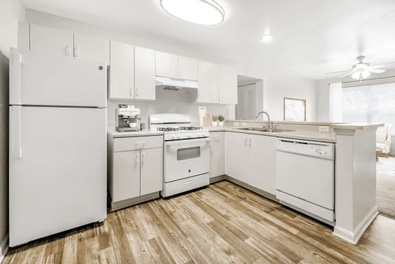 Kitchen with hardwood style flooring, white appliances, white cabinets, and breakfast bar