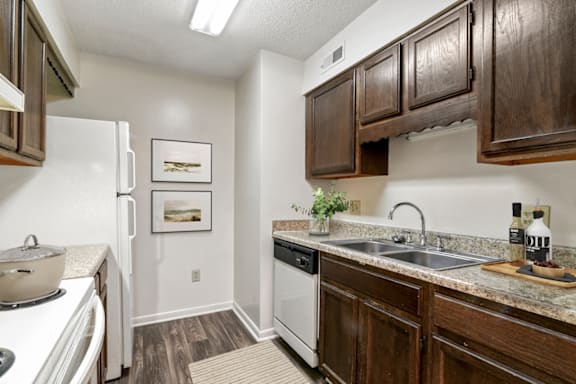 a kitchen with dark wood cabinets and white appliances at Eastchester Ridge Apartments, High Point, North Carolina