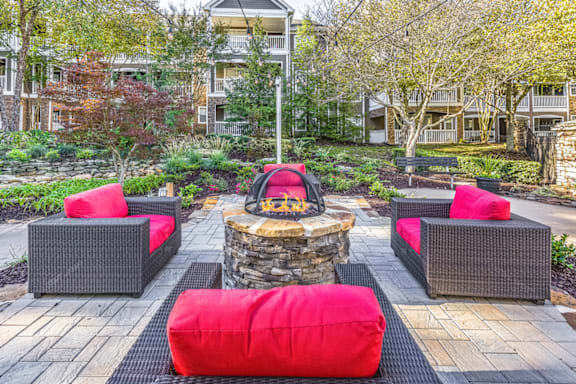 a seating area with a fire pit in the middle of a brick patio