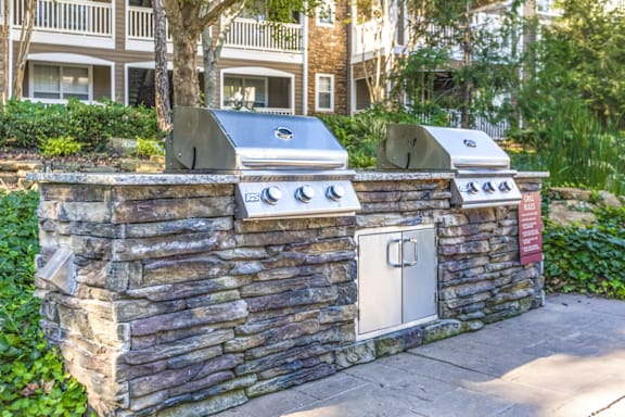 a backyard barbecue area with a stone wall and two stoves