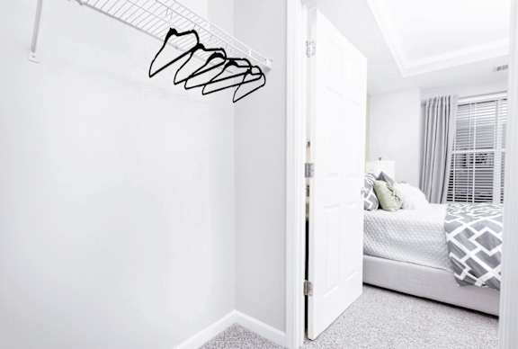 A white bedroom with a bed and a white wall.