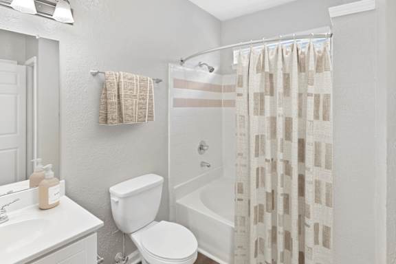 A white bathroom with a toilet, sink, and shower curtain.