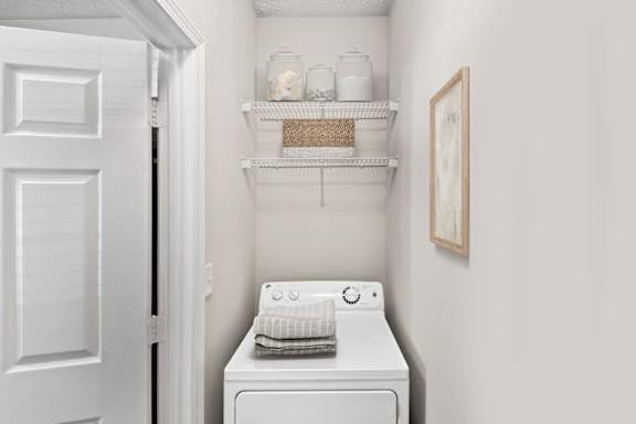 A white washing machine sits in a small laundry room.