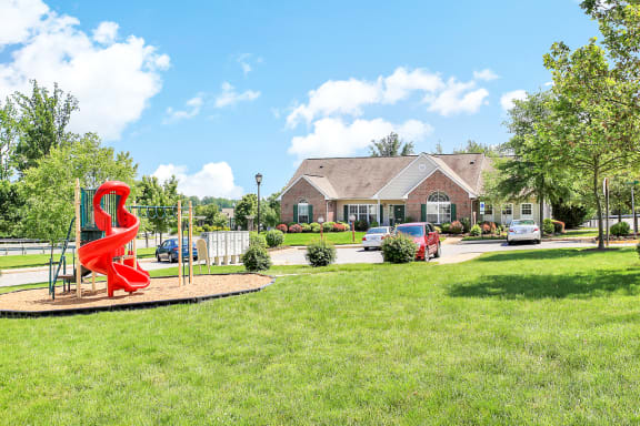 a playground with a red spiral slide in front of a house