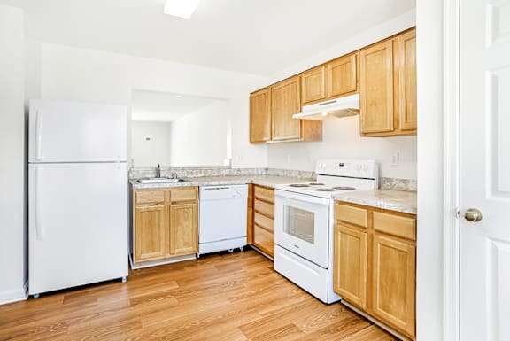 A kitchen with white appliances and wooden cabinets.