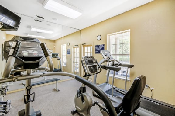 Fitness center equipped with multiple exercise machines, dumbbell free weights and mirror wall