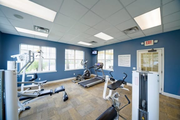 Fitness center with cardio equipment and large windows for natural lighting