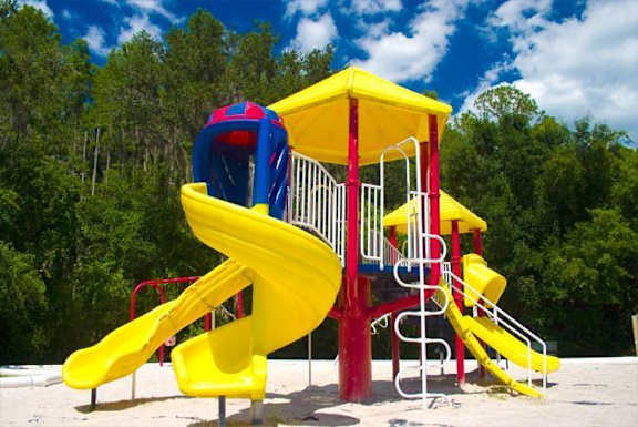 Colorful Playground  on Sand with Treeline in the Background