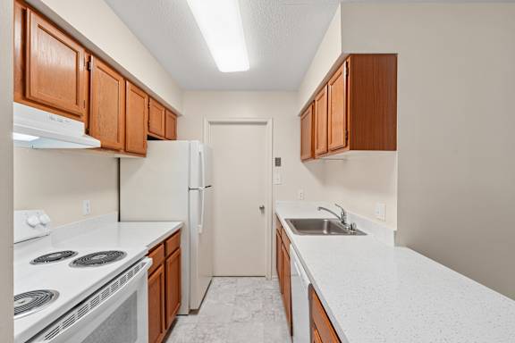 A kitchen with white countertops and brown cabinets.
