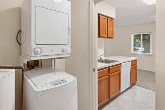 A white dishwasher is in a kitchen with wooden cabinets.