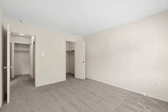 A room with a carpeted floor and two doors.